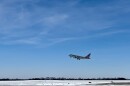 An American Airlines jet takes off from the Columbia Regional Airport runway. There is snow on the ground. 
