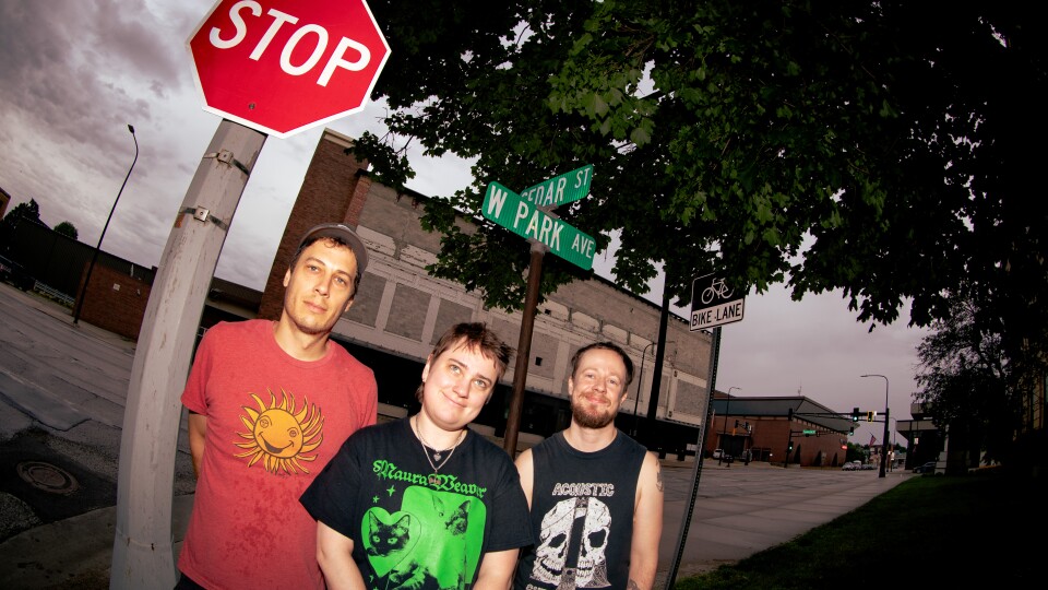 Three people standing in front of a STOP sign 