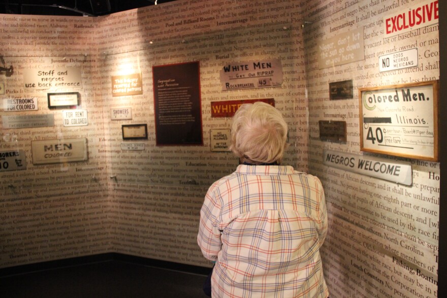 A visitor to the museum looks at signs that indicate Jim Crow-era segregation laws.