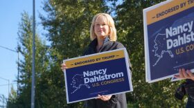a woman holding a sign that says "Nancy Dahlstrom U.S. Congress"