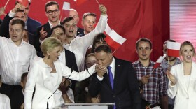 President Andrzej Duda kisses the hand of his wife Agata Kornhauser-Duda, in Pultusk, Poland, Sunday night. Duda won re-election by a narrow margin.
