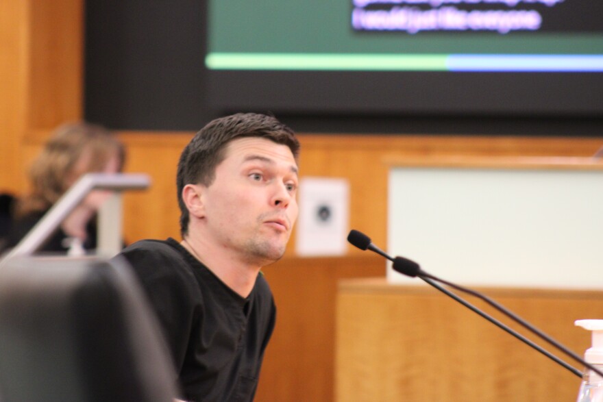 Man in black shirt speaks into microphone