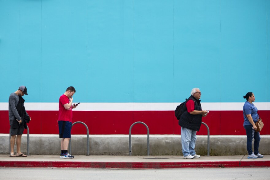 A line of customers, spaced apart from one another in accordance with social distancing guidelines, wait to enter an HEB grocery store in South Austin during the coronavirus pandemic.