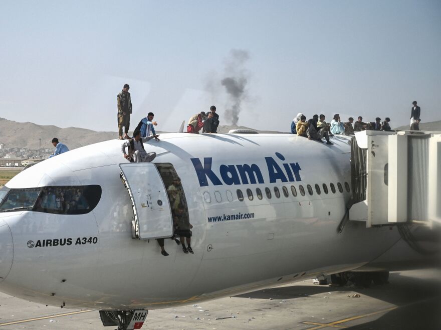 Afghan people climbed atop a plane at the Kabul airport on Aug. 16, 2021. Thousands of people mobbed the city's airport trying to flee before the U.S. withdrawal.