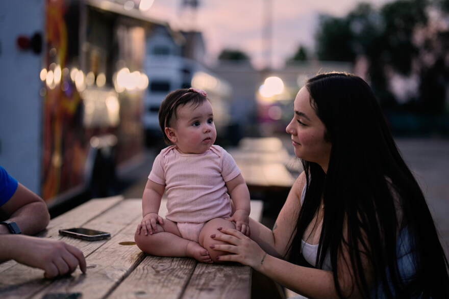 A Venezuelan mother sits with her daughter among food trucks Tuesday, July 14, 2026, in Midvale, Utah.
