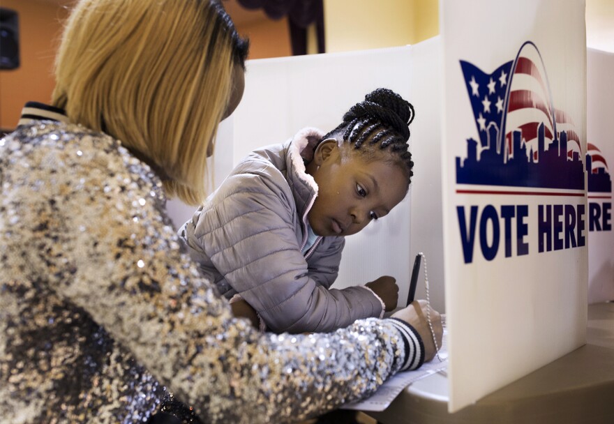 Jumira Moore, 8, watches as her mother, Timira Saunders, fills out a ballot at Central Baptist Church in St. Louis in November 2016.