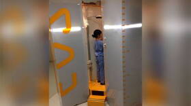 Dr. Karen Myung demonstrates how a patient would stand in the EOS machine.