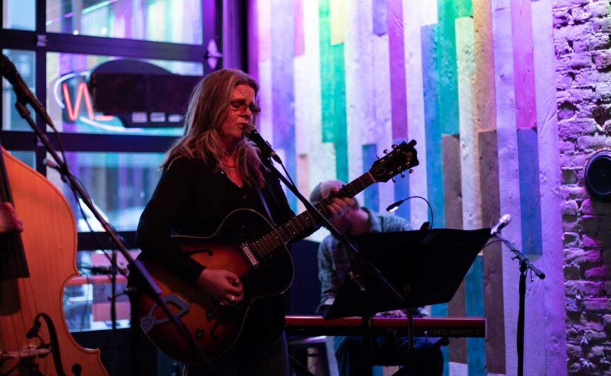 Woman playing guitar and singing into a microphone