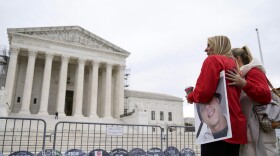 FILE - Jen Trejo holds a photo of her son Christopher as she is comforted outside the Supreme Court where signs in the shape of grave headstones, with information on people who died from using OxyContin, line a security fence, Monday, Dec. 4, 2023, in Washington. The Supreme Court on Thursday, June 27, 2024, rejected a nationwide settlement with OxyContin maker Purdue Pharma that would have shielded members of the Sackler family who own the company from civil lawsuits over the toll of opioids but also would have provided billions of dollars to combat the opioid epidemic.