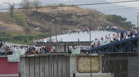 Inmates shout from the rooftop of the Zone 8 Deprivation of Liberty Center to demand the return of Los Choneros leader Adolfo Macías, alias "Fito," in Guayaquil, Ecuador, Monday, Aug. 14, 2023. Authorities moved the leader of one of Ecuador's most powerful gangs into a maximum-security prison Saturday, three days after the assassination of a presidential candidate who had denounced threats from the feared criminal. (AP Photo/Martin Mejia)