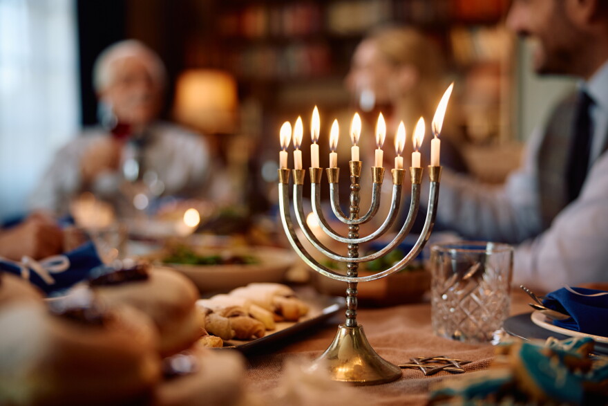 Lit candles in menorah during Hanukkah celebration. The family is in the background.