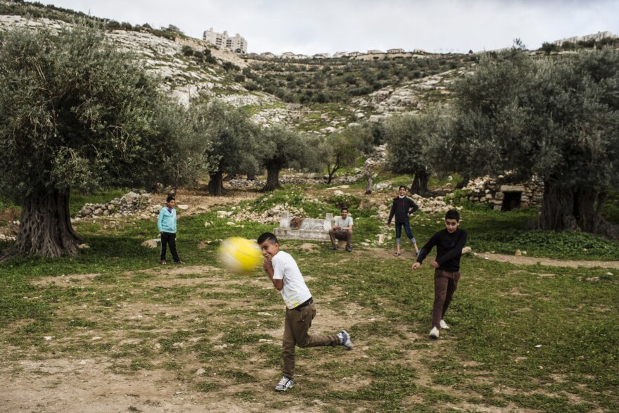 Palestinian children play in Marda, with the Jewish settlement of Ariel on the ridge in the background. Prior to the late 1970s, the land on which Ariel sits was farmed by nearby Palestinian families.