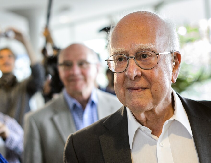 British physicist Peter Higgs, right, arrives for the opening of a seminar to deliver the latest update in the 50-year bid to explain a riddle of fundamental matter in the search for a particle called the Higgs boson.