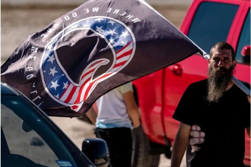  A man carries a flag with the letter “Q,” signifying the QAnon conspiracy, at a “Trump Train” event in San Antonio on Nov. 1, 2020. 