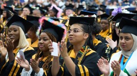 A diverse group of students in graduation attire clapping