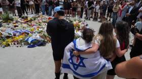 People gather around a growing flower tribute to shooting victims outside the Bondi Pavilion at Sydney's Bondi Beach, Monday, Dec. 15, 2025, a day after a shooting. (Mark Baker/AP)