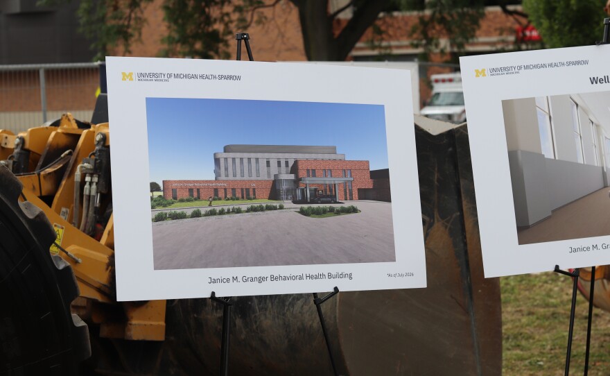 A rendering of the Janice M. Granger Behavioral Health Building is displayed on an easel in front of construction equipment.