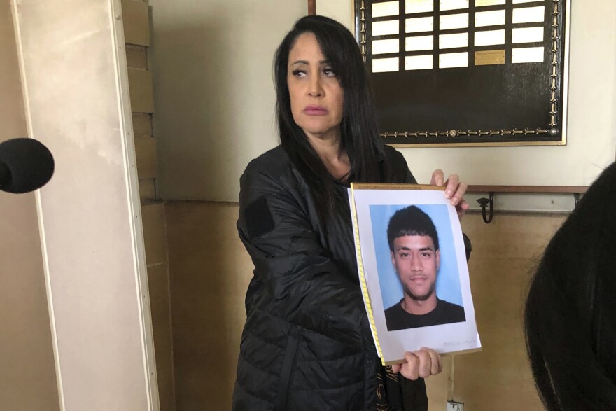 Lt. Deena Thoemmes, the lead homicide investigator for the Honolulu Police Department's Criminal Investigation Division, holds a photo of Jacob Borge, one of two suspects in a shooting Saturday, April 15, that killed two people and injured three others after a cockfight, during a news conference in Honolulu, Tuesday, April 18, 2023. (AP Photo/Audrey McAvoy)