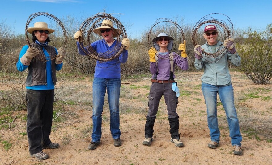 Desert Fence Busters volunteers displaying their recently removed, hand-rolled barbed wire.