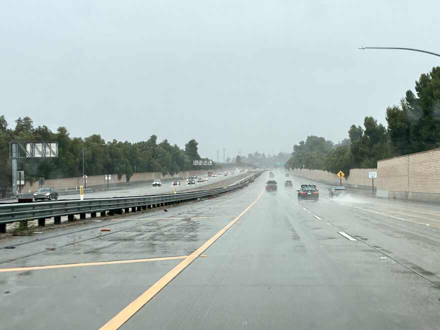 A view looking out of a vehicle windshield at a freeway during a rainstorm. 