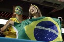 Two girls with green and yellow face paint hold a Brazilian flag