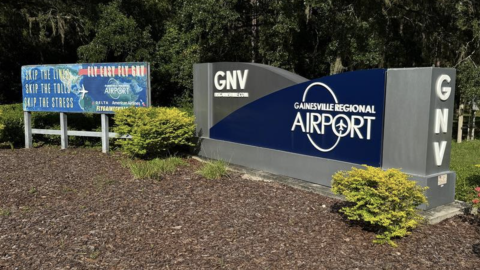 A sign at the entrance to Gainesville Regional Airport with an accompanying banner that reads “Fly easy, Fly GNV.” (Stryker Anderson/WUFT News)