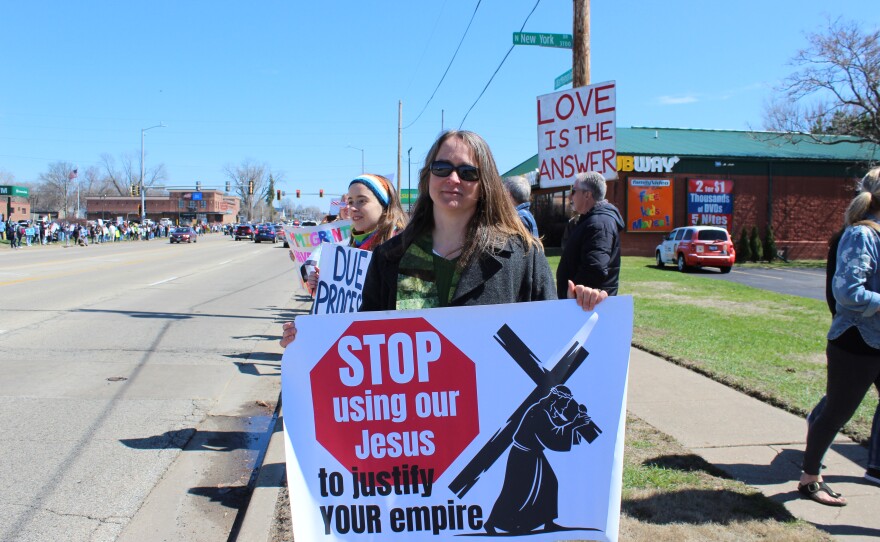 Pastor Jolene Miller from Roanoke Mennonite church in Woodford county Ill. holds a sign that says "Stop using our Jesus