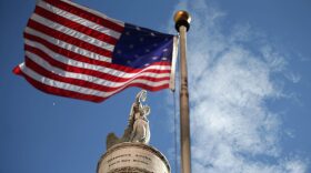 A U.S. flag with 15 stripes and 15 stars, like the one that was flown Fort McHenry during the War of 1812, frames the Battle Monument during the Star Spangled Spectacular Sept. 12, 2014, in Baltimore. (Chip Somodevilla/Getty Images)