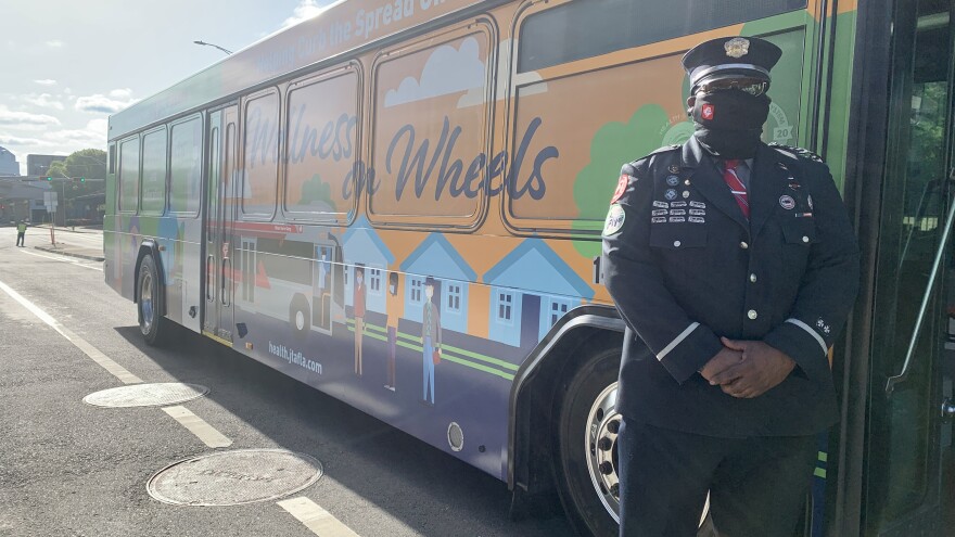 A city employee stands next to a repurposed vaccine bus. 