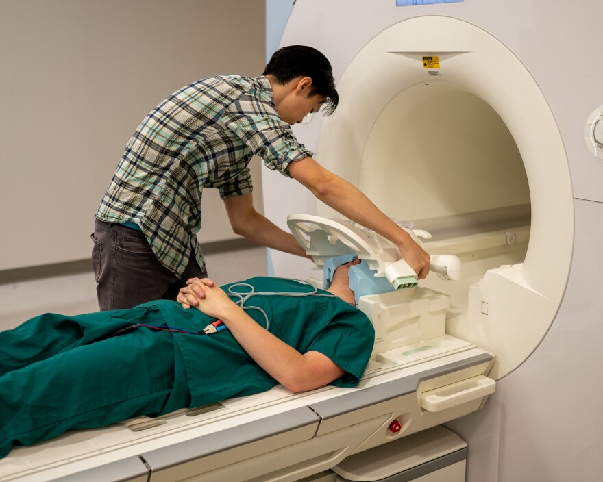 Ph.D. student Jerry Tang prepares to collect brain activity data in the biomedical imaging center at The University of Texas at Austin.