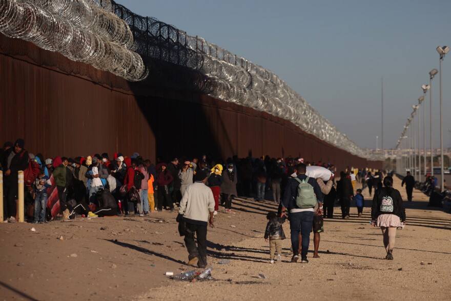 Asylum-seeking migrants wait at the border wall to be processed by U.S. Customs and Border Protection after crossing the Rio Grande River into the United States in El Paso, Texas, U.S., December 21, 2022.