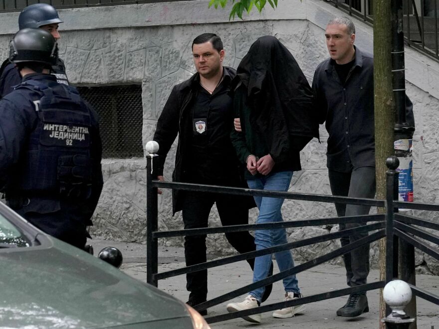 Police officers escort a seventh grade student who is suspected of firing several shots at a school in Belgrade.