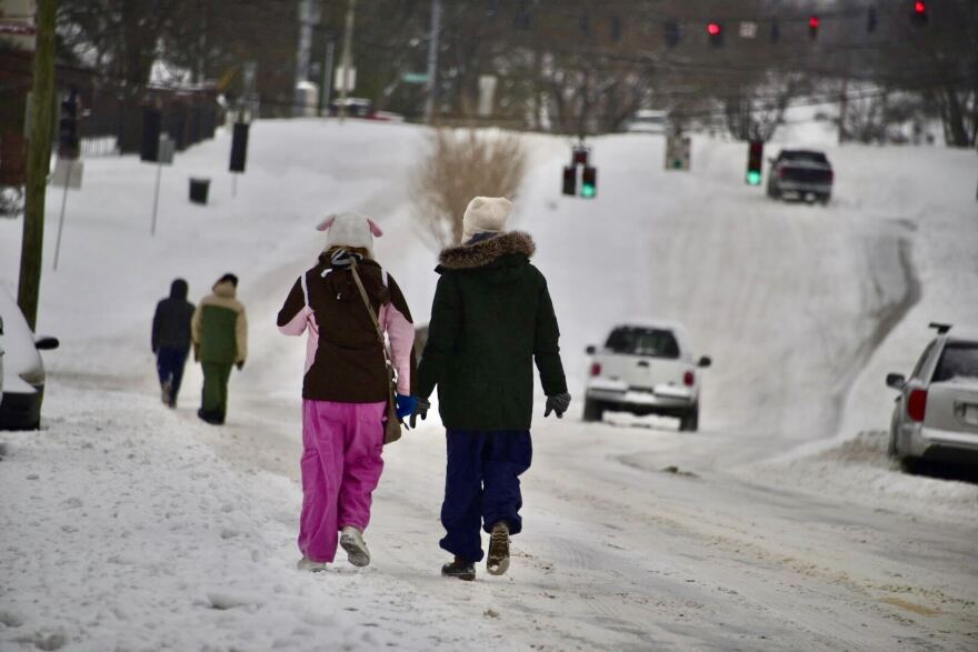 People walk down a snowy road in Louisville.