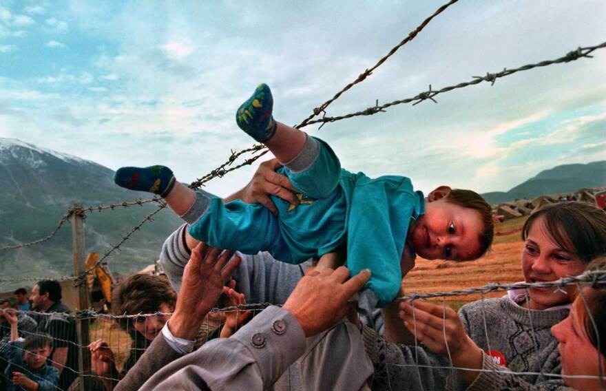 This photo by Carol Guzy of The Washington Post of a child being passed over a wall at an Albanian refugee camp in 1999 won a Pulitzer Prize.