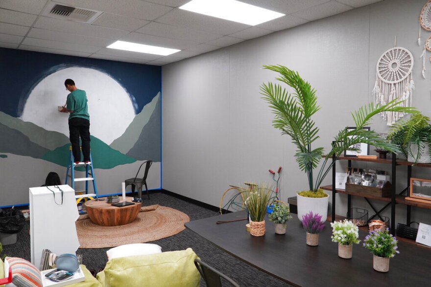 A man paints a mural of a giant moon over mountains during construction of University High School's Well Space in Irvine, Calif., on July 28, 2022. When school starts, the room is to be staffed full-time with a counselor or mental health specialist. (AP Photo/Eugene Garcia)