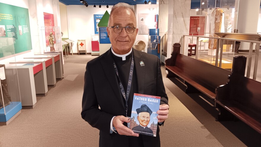 Monsignor David LiPuma, Pastor of Our Lady of Victory National Shrine and Basilica in Lackawanna, holds a copy of Father Baker, A Friend to All, a children's book created by an OLV employee and distributed to Catholic school students to coincide with Read Across America Week.