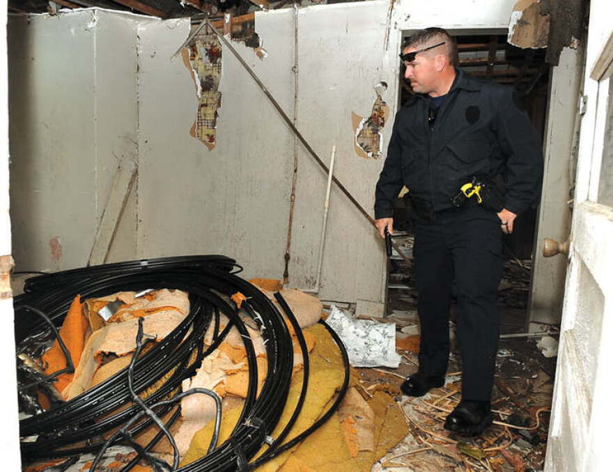 Winchester Police officer David Aldridge looks at some of the wire stolen from the AT&T building at 203 Forrest Ave. over the weekend. The wire was discovered in an abandoned house at the intersection of W