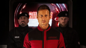 Still from the 2025 film The Running Man, featuring actor Glen Powell as his character Ben Richards [pictured at center].