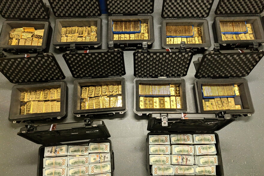 Open boxes full of gold bars and cash.