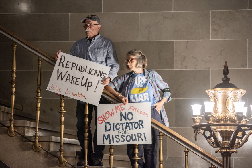 David Fortel and Hope Tinker hold homemade signs during a September 2025 protest in the Missouri Capitol rotunda.