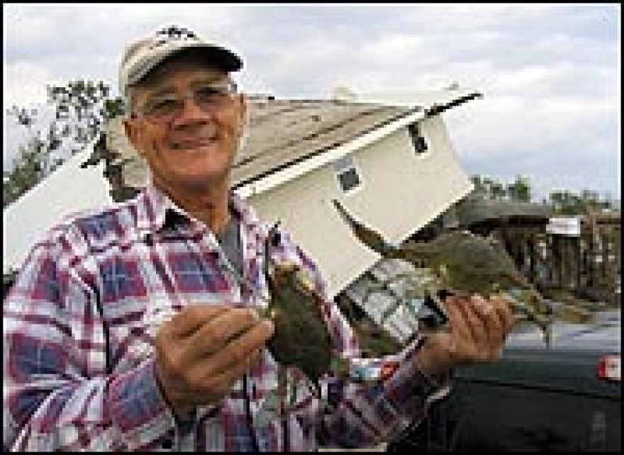 Commercial fisherman Charles Morales, 65, holds up freshly caught blue crabs as he stands in front of damaged buildings on Delacroix Island, Louisiana. He worries about the future of the Isleno communities, and where their inhabitants will go.