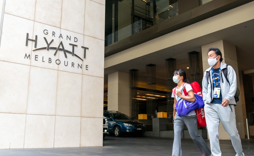 Players and their entourages emerge from the Grand Hyatt Melbourne on Thursday. A positive case was discovered at one of the Australian Open quarantine hotels, with some 500 Australian Open players, officials and support staff told to quarantine and get tested.