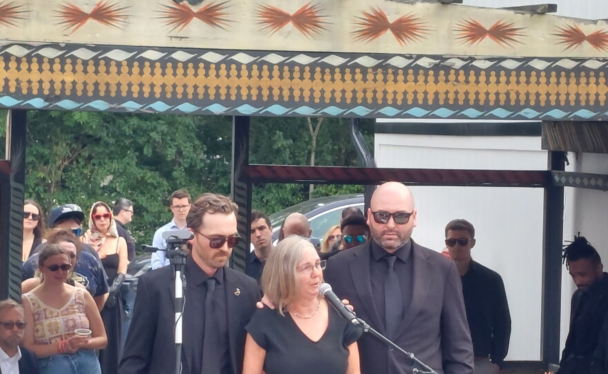 Tommy York's wife, Julie Harkema speaks at her husband's memorial with sons Aedan (left) and Lincoln (right) by her side.