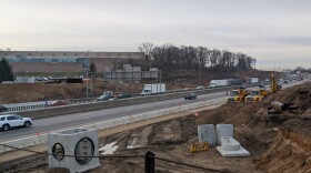 Cars and trucks drive through a construction zone.