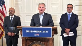 North Carolina Gov. Josh Stein, center, flanked by Health and Human Services Secretary Dr. Dev Sangvai, left, and Undue Medical Debt Vice Chair Jose Penabad, speaks about the elimination of medical debt through an initiative involving hospitals and Medicaid at the Executive Mansion in Raleigh, N.C., Monday, Oct. 13, 2025. (AP Photo/Gary D. Robertson)