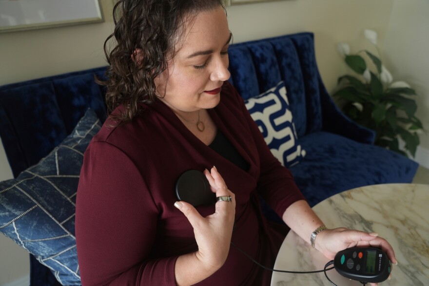 Brandy Ellis charges a pacemaker-like device that was installed in her chest as part of an experimental treatment for depression, on Thursday, July 24, 2025, in Delray Beach.