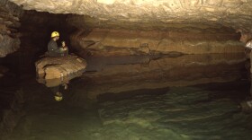 Caver Mary Laycock sits on a rock on the edge of Windy City Lake, the largest and deepest body of water in Wind Cave. At this point, the cave intersects the Madison Aquifer more than 600 feet below the surface.