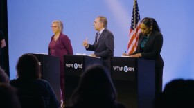 Three candidates stand at podiums during a debate