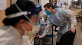 Registered Nurse Richard Moses looks at his computer while working in a COVID-19 unit at Providence Holy Cross Medical Center in the Mission Hills section of Los Angeles, Thursday, Nov. 19, 2020.