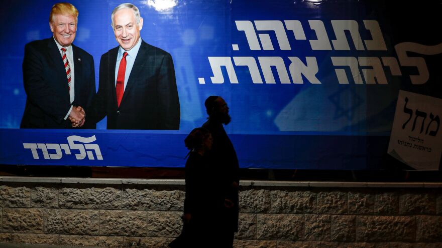 Pedestrians pass an Israeli election billboard for Prime Minister Benjamin Netanyahu's Likud Party, which depicts him shaking hands with President Trump. The caption written in Hebrew reads: "Netanyahu, in another league."